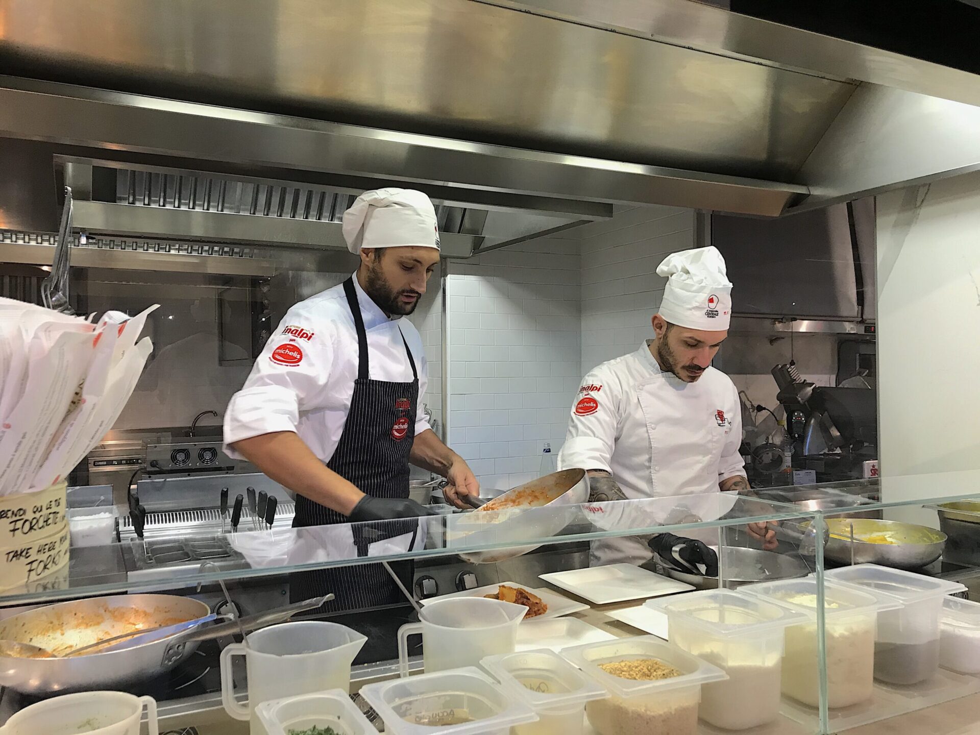 Two Italian chefs cooking pasta in Italian food market